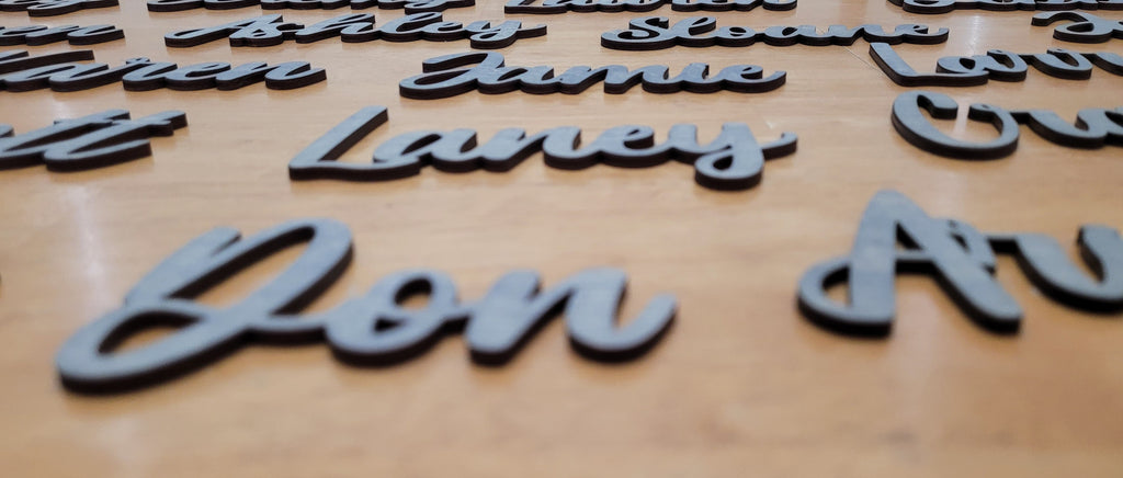 Close-up of custom grey 3D raised lettering showing the names 'Don Av' and 'Laney' in sharp focus with other names blurred due to depth of field.