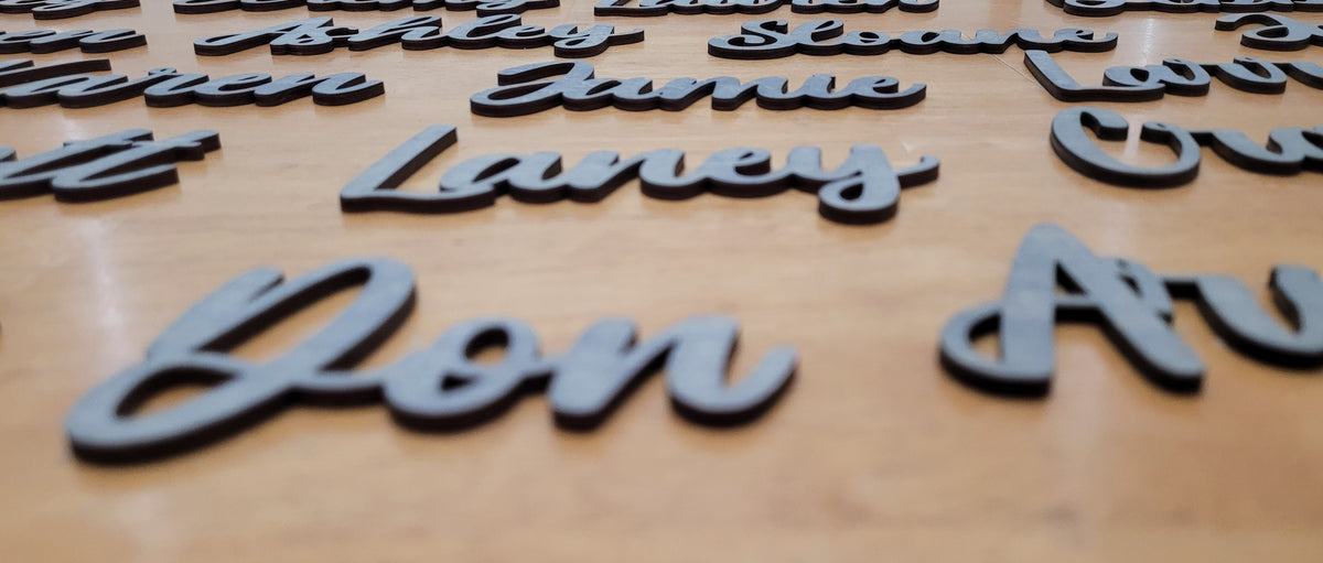 Close-up of custom grey 3D raised lettering showing the names 'Don Av' and 'Laney' in sharp focus with other names blurred due to depth of field.