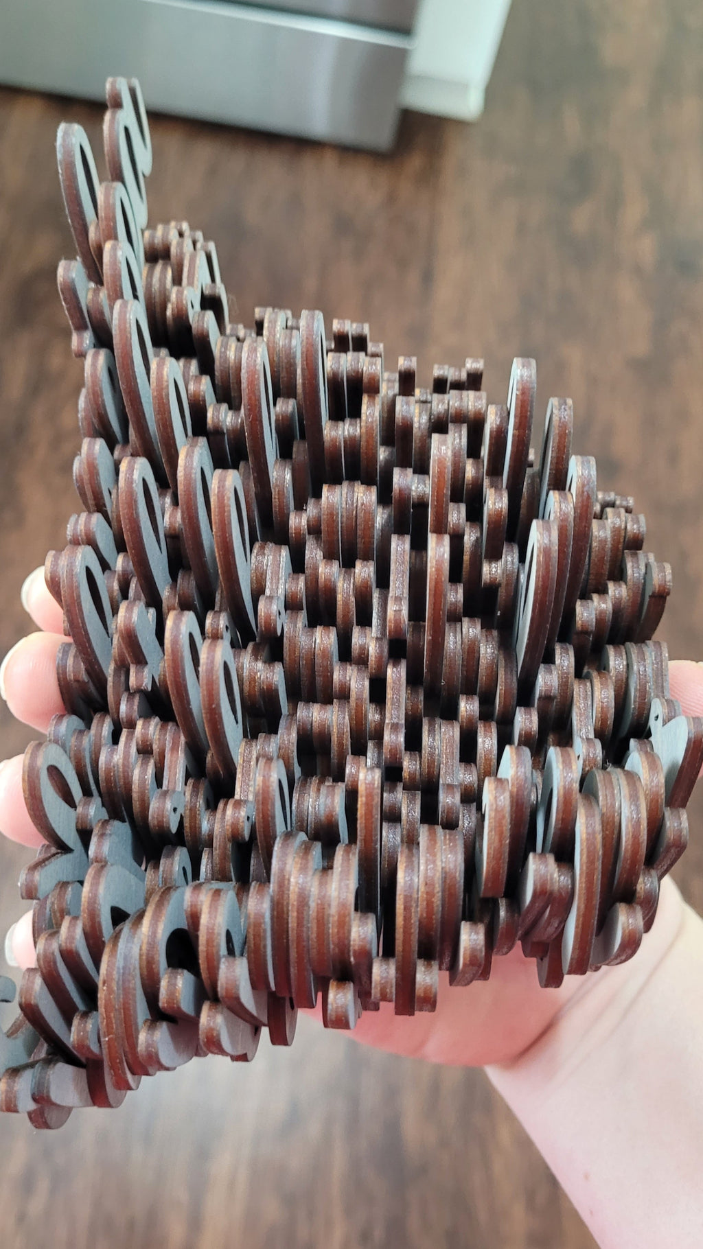 A hand holding a large stack of grey washed wood names.